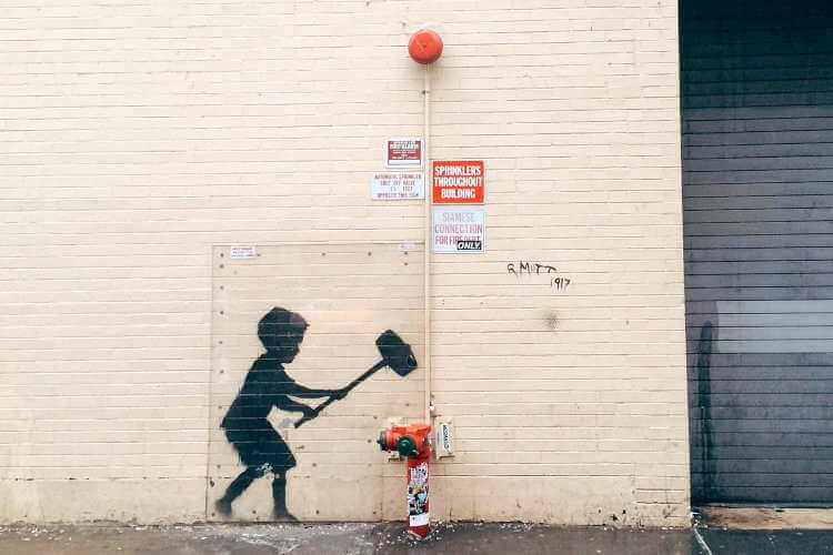 Banksy grafika chłopiec z młotem uderza w hydrant
